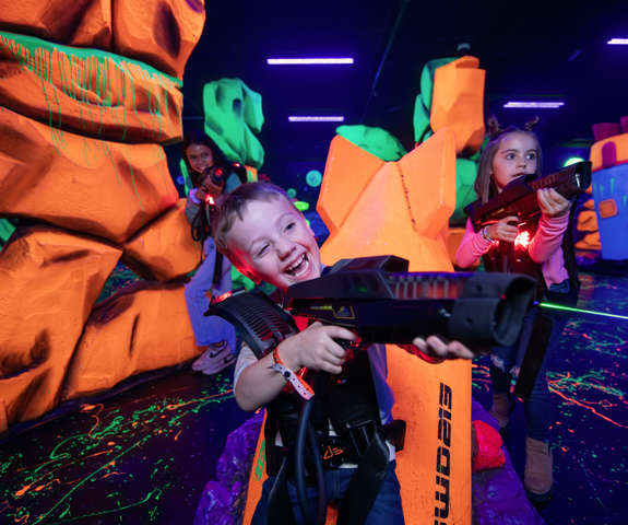 Kids playing laser tag under neon lights